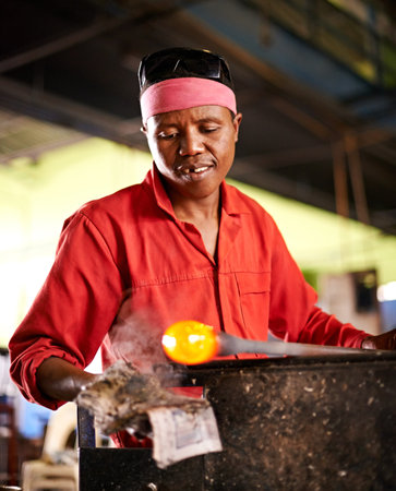 Glass, blowing and black man in workshop with process, creative small business or handmade form. Art, product shape and glassblower in factory for sustainable craft, design tools and sculpture glowの写真素材