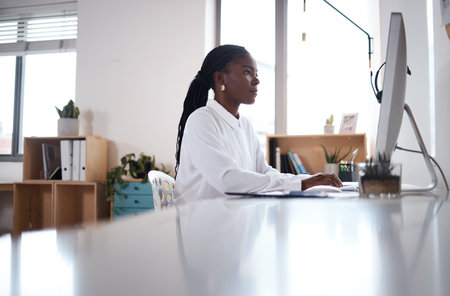 Office, black woman and typing with computer for call center, sales research and customer information. Career, business person and consultant with digital for online training, crm software or readingの写真素材