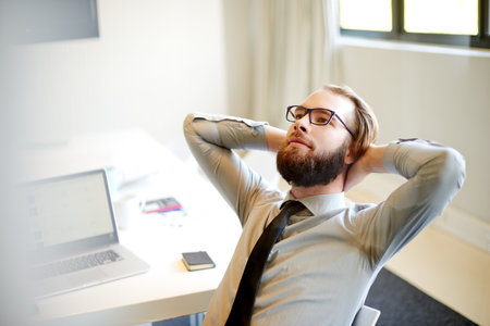 Business man, relief and done at office for report, deadline and admin at financial agency. Person, rest and relax for project management, accounting or finished with proposal in corporate workplaceの写真素材