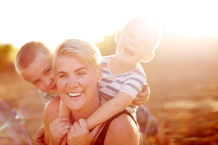 Portrait, outdoor and mother with boys, hug and bonding together with smile, journey and funny. Family, single parent and mama with kids, embrace and play with break, happiness and support with careの写真素材