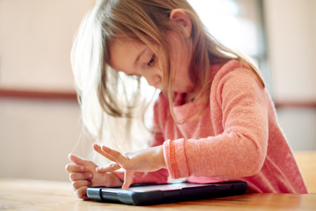 Kid, student and press on tablet in classroom for streaming lesson, elearning website and drawing. Child, girl and digital with online education, reading ebook and studying application for assessmentの写真素材