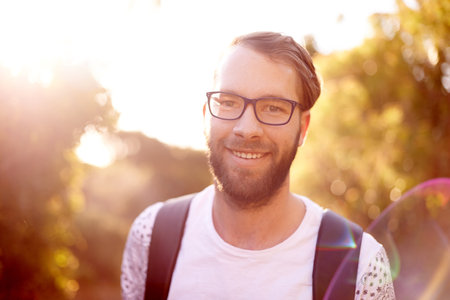 Portrait, smile and hiking with man in nature for explore, summer vacation and adventure. Health, trekking and travel with person outdoors on path for wellness, fitness journey and eco tourismの写真素材