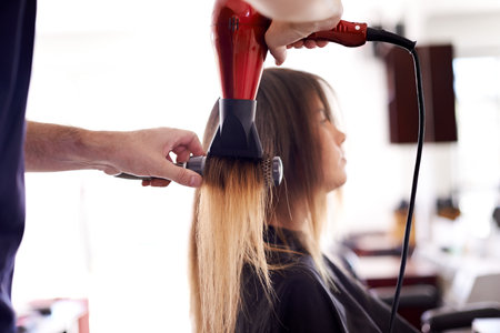 Hair, salon and woman with hairdryer with hairdresser for wellness, beauty and cosmetics service. Parlor, beautician and worker with customer for maintenance, treatment and drying for hairstyleの写真素材