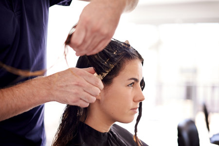 Woman, hairstylist and hands combing wet for styling, trim or preparing for dye, blow dry or treatment in salon. Professional hairdresser with client or person for booking, maintenance and servicesの写真素材