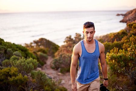 Trail, travel and hiking with man in nature for explore, summer vacation and adventure. Health, trekking and ocean with person outdoors on path for wellness, fitness journey and eco tourism.の写真素材