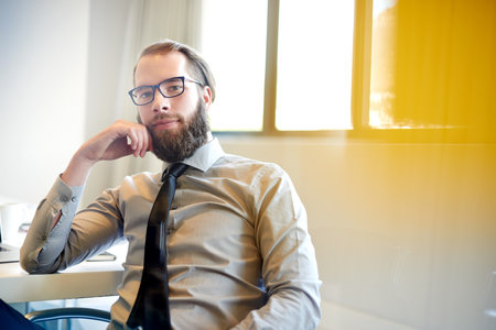 Accounting, portrait and serious with business man in office for financial management or planning. Beard, finance and glasses with confident bank employee in workplace for economic investmentの写真素材