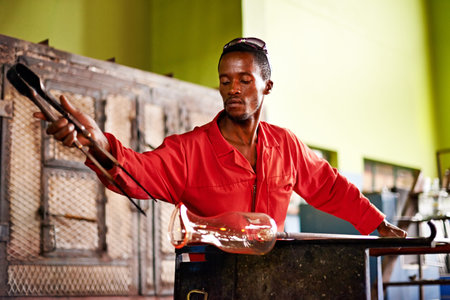 Glass, art and black man in workshop with tools for small business, craft or handmade technique. Creative, product shape or glassblower in factory for sustainable process, design or bottle sculptureの写真素材