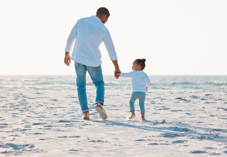 Dad, beach or holding hands with toddler for walk, bonding or support of family trust on ocean coast. Back view, father and child or kid strolling with parent on sandy shore for summer holiday by seaの写真素材