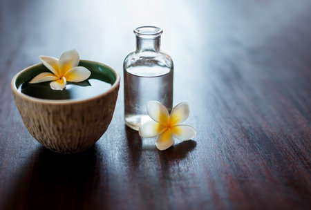 Flower, spa and essential oil on table with natural product, water and bowl for fragrance. Holistic health, hospitality service and mockup space for aromatherapy, self care and luxury wellness salonの写真素材
