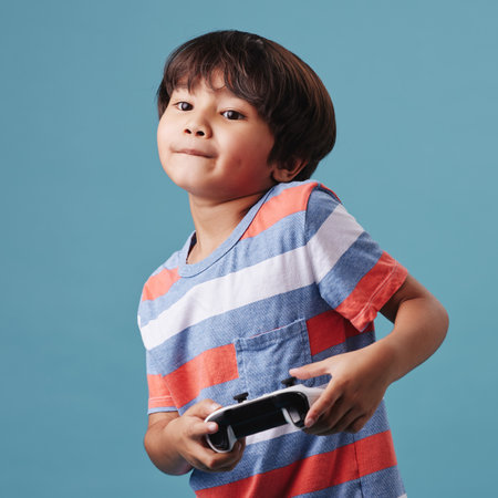 Japanese boy, child and studio background with joystick for streaming service, video games and esports. Male person, childhood and concentrate for entertainment, fun and growth or developmentの写真素材