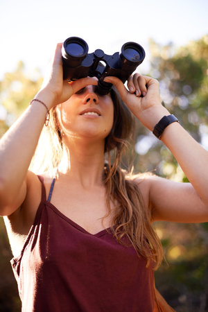 Travel, trekking and woman with binocular in nature for adventure, holiday or bird watching in...
