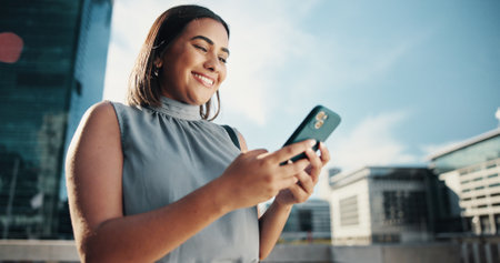 City, businesswoman and happy with smartphone for search, information and real estate agent. Low angle, female person and realtor with mobile for property listing, application and scroll on websiteの写真素材