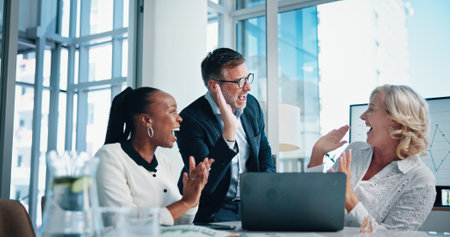 Business people, teamwork and high five for celebration, excited or achievement with laptop in office. Win, manager and hands together for financial growth, applause or success with investment targetの写真素材