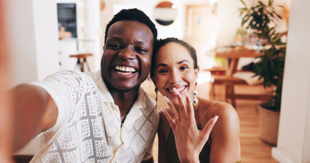 Happy, portrait and interracial couple with selfie for marriage proposal, ring or save the date at home. Excited man, woman or lovers with smile in joy for picture, memory or yes together at houseの写真素材