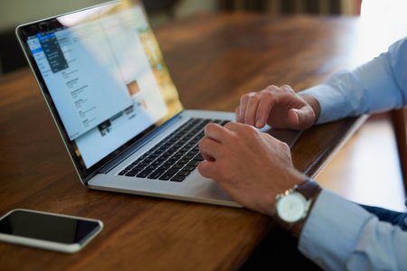 Business, hands and online with laptop in home for remote work, checking notifications and writing email. Professional, person and technology in dining room with research, screen and blog websiteの写真素材