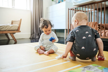 Babies playing, game and kid toys for mobility development and learning together in a home bedroom. Nursery, toy brick and cute children with block play thing and activity in a house on the floorの写真素材