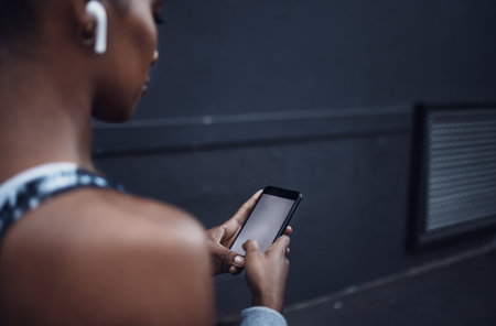 Woman, runner and phone with earphones in city with blank screen for mockup space, exercise or music. Girl, smartphone and audio streaming for workout, fitness and health on sidewalk in Costa Ricaの写真素材