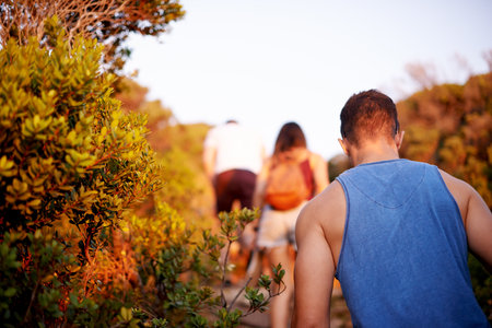 Friends, back and hike on mountain for countryside, travel or adventure to explore nature. Journey, group of people and vacation with natural environment for walking, hobby or bonding togetherの写真素材