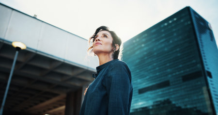 Morning, inspiration and business woman in city with idea, brainstorming and career insights. Thinking, low angle and confident person for company future, urban development and job opportunityの写真素材