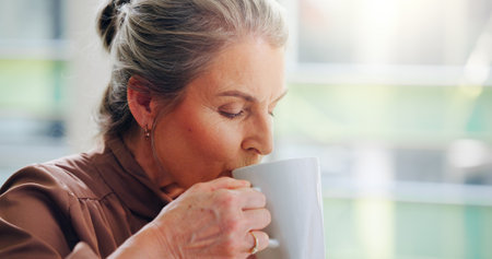 Mature woman, drink and morning with coffee at office for beverage, start or cappuccino. Senior, female person or business employee with latte, caffeine or mug for sip, breakfast or liquid at workの写真素材
