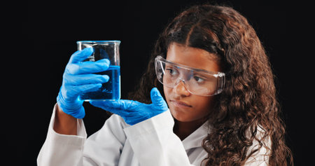 Girl, scientist and liquid with beaker in studio for experiment, test or exam on a dark background. Female person, teenager or chemist with chemical compound for science discovery, results or alchemyの写真素材