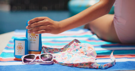 Sunscreen, sunglasses and hat with hand at swimming pool for uv rays protection, spf cream or summer vacation. Sunblock lotion, dermatology and closeup of child outdoor at holiday resort for skincareの写真素材