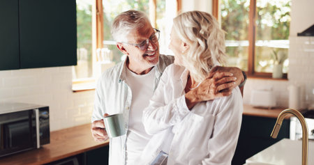 Senior couple, hug and coffee in home, love and romantic conversation with happy wife in kitchen. Elderly people, smile and support by listening for healthy marriage, tea cup and retirement embraceの写真素材