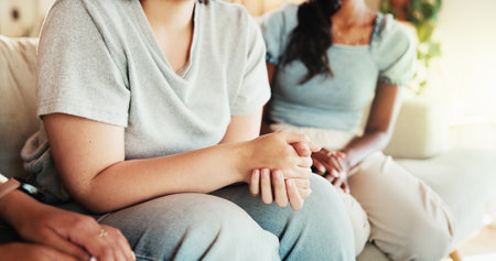 Women, hands or talking with discussion on sofa for care, support group or intervention at home. Closeup, female people or listening with friends on couch for confession, empathy or sympathy at houseの写真素材