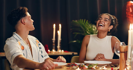 Couple, laughing and red wine on date at restaurant on valentines day, romantic dinner and celebration. People, alcohol glass and cuisine meal for fine dining, anniversary and relationship commitmentの写真素材