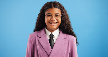 Studio, laughing and child in portrait for education, clothes and back to school with mockup space. Smile, student and girl with fashion for uniform, learning energy and academy by blue backgroundの写真素材