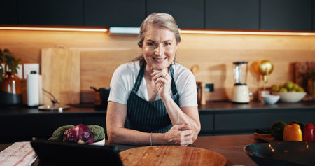 Home, portrait and woman in kitchen, tablet or food with nutrition, social media or confidence. Senior person, apartment and chef with tech, culinary skills and hobby with ingredients and smileの写真素材