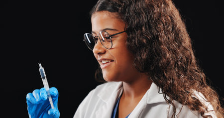 Child, play and doctor with syringe in studio of vaccine, drug injection and medicine treatment. Smile, kid and needle of healthcare safety, virus prevention or medical innovation on black backgroundの写真素材