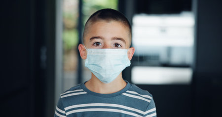 Sick, kid and portrait with mask in home for virus transmission, disease prevention and health precaution. Boy child, face protection and medical risk with respiratory illness or influenza infectionの写真素材