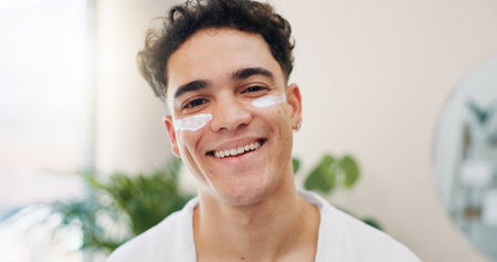 Home, portrait and happy man with cream for skincare, wellness and hydration benefits in morning. House, routine and male person with sunscreen for cosmetics, beauty treatment or moisturizer for faceの写真素材