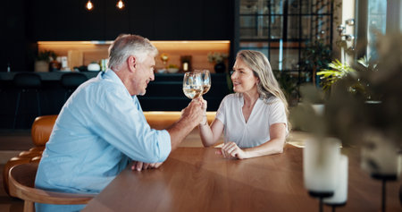 Cheers, happy and mature couple with champagne in home for celebration, romance and marriage on date. Love, commitment and man with woman for glass of wine with anniversary toast together in house.の写真素材