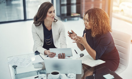 Decision, documents and meeting with business women in office together for planning or strategy. Explain, laptop and tablet with accounting colleagues in financial workplace for budget discussionの写真素材