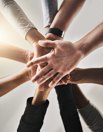 People, hands and below with team for support, motivation or unity in solidarity. Low angle, closeup or community group in huddle with stack for social inclusion, collaboration or cohesion togetherの写真素材