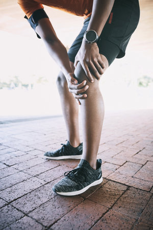 Person, hands and fitness with knee pain for injury, muscle strain and stretching accident by closeup. Urban, runner and discomfort with leg ache for anatomy, fibromyalgia or inflammation for workoutの写真素材