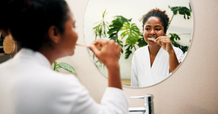 Oral hygiene, mirror and girl brushing teeth in home for morning routine, fresh breath or plaque removal. Reflection, person or getting ready in bathroom with dental care, mouth health or gum diseaseの写真素材