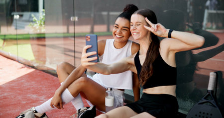 Sports, peace sign and selfie of friends on court for training, match and playing game. Fitness club, racket and happy women smile for exercise, workout and practice with photo for social mediaの写真素材