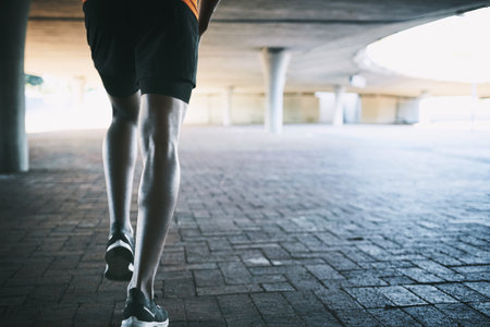 Outdoor, person and legs with running for fitness, cardio health and wellness with exercise by space. Back, urban and runner with training for marathon challenge, endurance and energy for workoutの写真素材