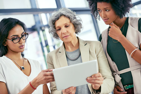 Meeting, planning and business women on tablet in office for website, research and online report. Company, discussion and people on digital tech for project management, feedback or proposal reviewの写真素材