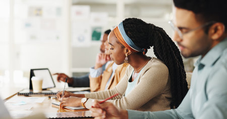 Business people, team and writing notes in training, workshop or watch video for development in...