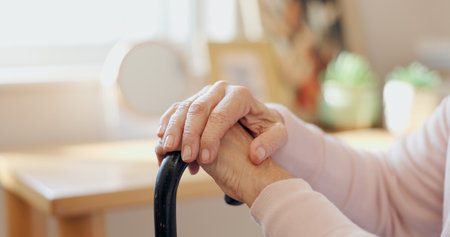 Cane, hands and senior woman with disability, healthcare and support in retirement home. Closeup, elderly patient and walking stick for pensioner with osteoporosis, arthritis and parkinson diseaseの写真素材
