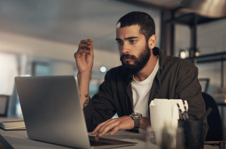 Creative, man and annoyed with laptop at desk in office for overtime, deadline or mistake. Thinking,...