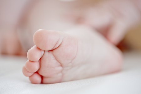 Sleeping, baby and closeup of foot, nursery and nap for development of child, growth and resting in house. Relax, young and infant on comfortable bed, dreaming and feet of newborn in apartmentの写真素材