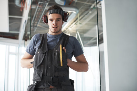 Contractor, handyman and headphones with portrait of man in office for renovation, maintenance and...