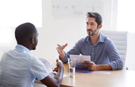 Meeting, office and business men for interview, job vacancy and career opportunity. Corporate HR, recruitment and people in discussion, talking and conversation for hiring process with documentsの写真素材