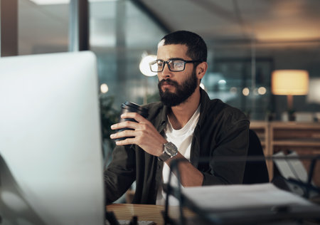 Business, man and computer with coffee in office for software update, programming website and research. Male person, caffeine drink and IT for online maintenance, reading report and solution deadlineの写真素材