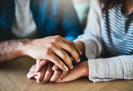 Empathy, couple and holding hands with love in home for depression, mental health support and trust. Closeup, people and comfort at table with healing, console or connection for relationship in houseの写真素材